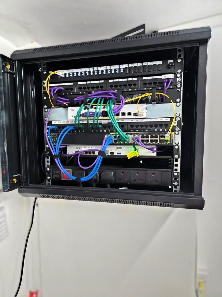 Wall-mounted network cabinet with patch panel and switching, labelled and commissioned